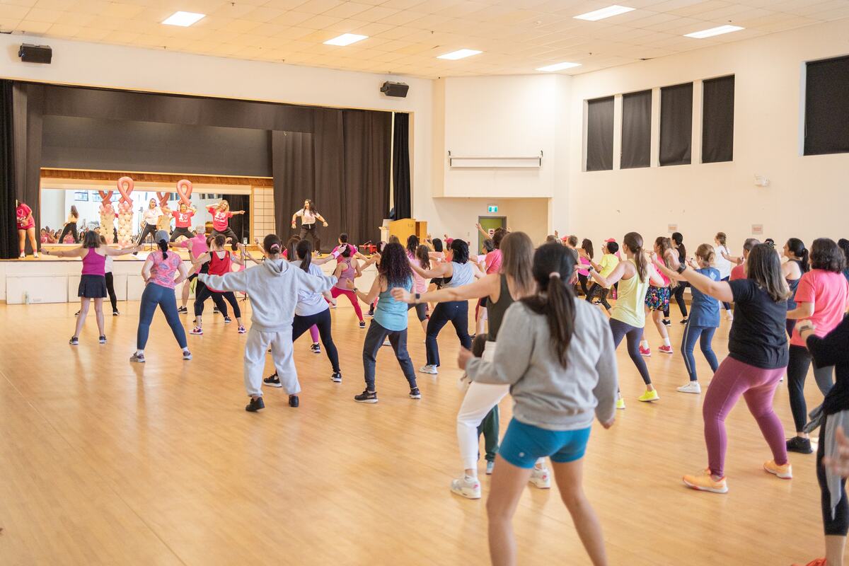 Dancers spread across the wood floor with the instructors up on stage behind them
